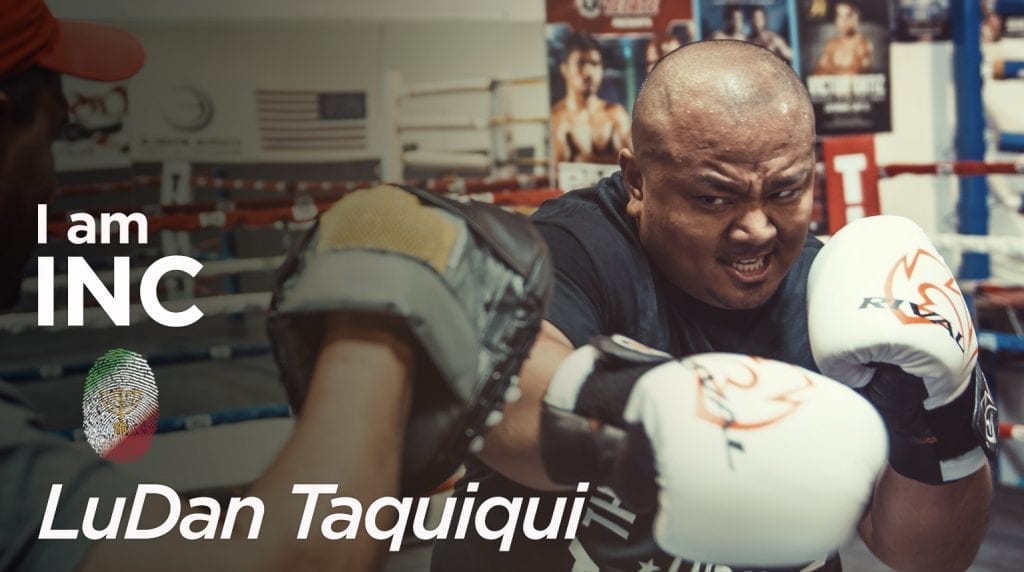 Man in a boxing ring with gloves with an intense look on his face with text overlay I am INC, LuDan Taquiqui.