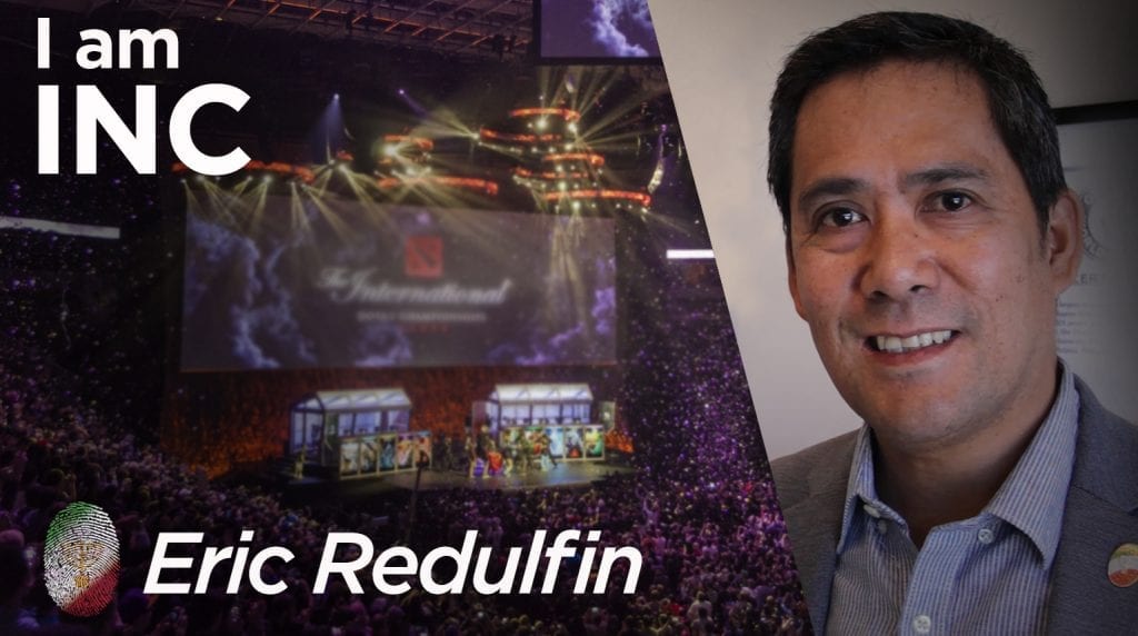 Man smiling and a arena with a big screen filled with people with text overlay I am INC, Eric Redulfin