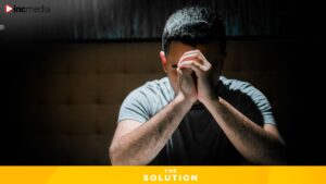 A man appears sad as he sits with his head on his clasped hands